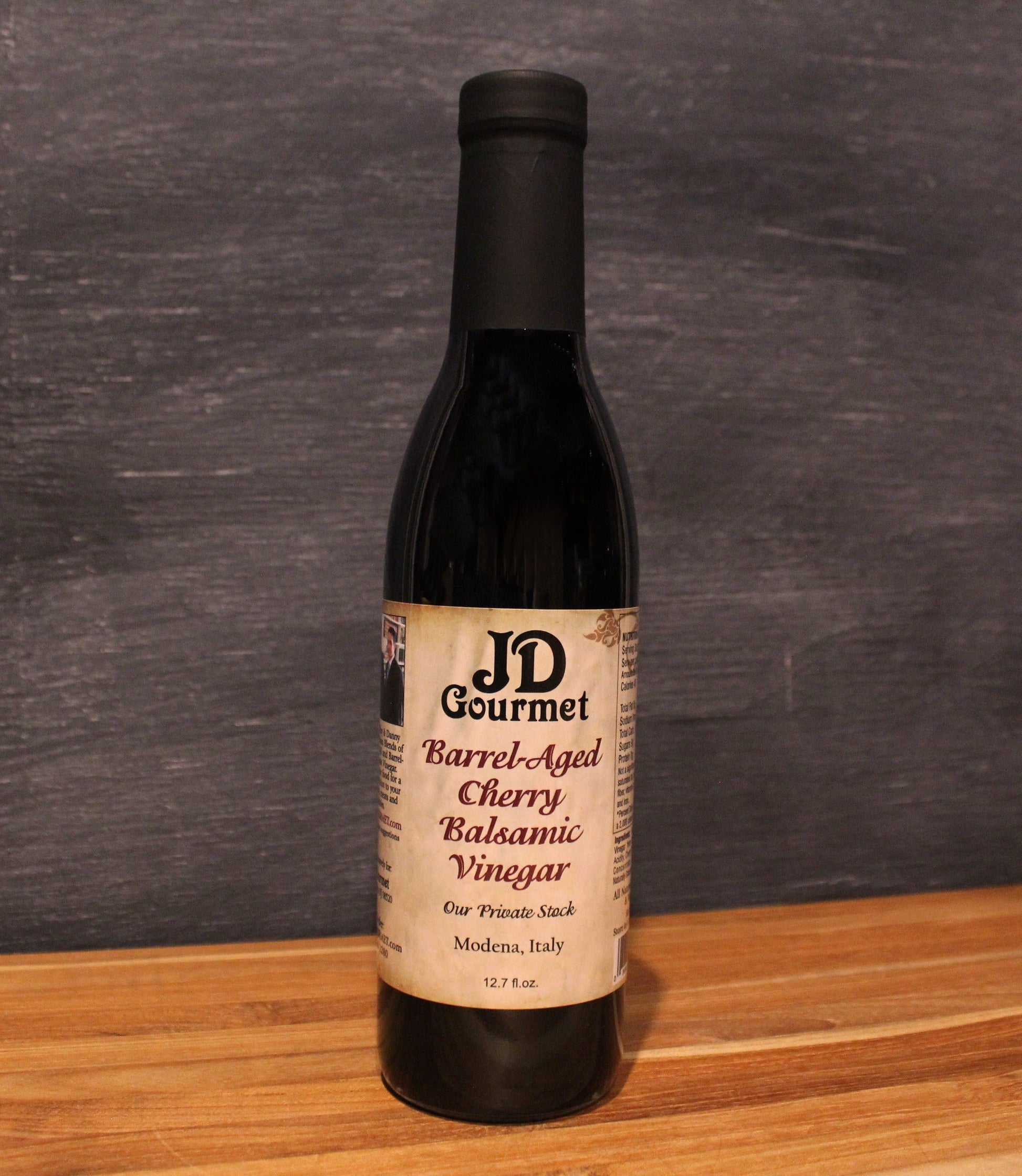 JD Gourmet Cherry Balsamic Vinegar — dark glossy balsamic in a clear bottle, dark sweet cherries, Modena