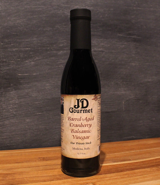 JD Gourmet Cranberry Balsamic — deep glossy dark balsamic in a clear glass bottle, made with real cranberry