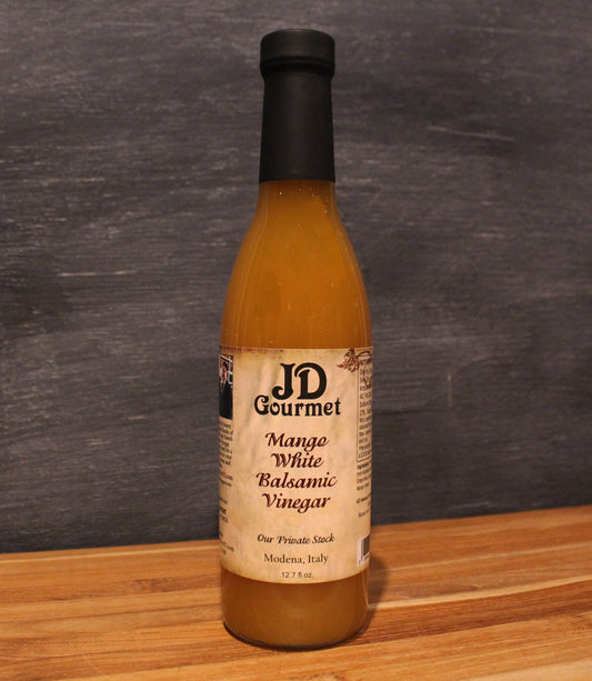 Clear bottle of JD Gourmet Mango White Balsamic Vinegar, golden white balsamic blended with ripe Alfonso mango