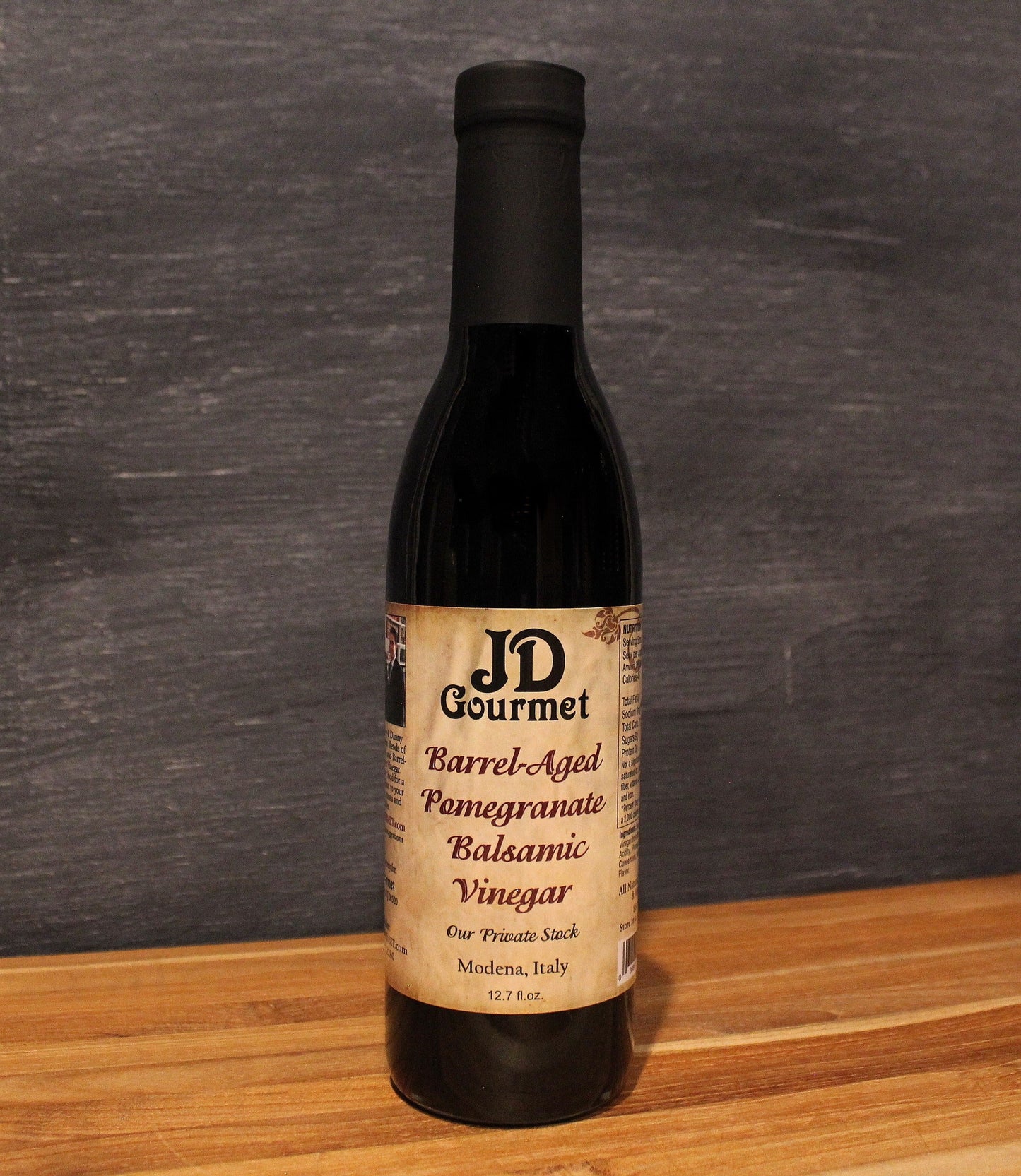 Bottle of JD Gourmet pomegranate balsamic vinegar, deep ruby red and glossy