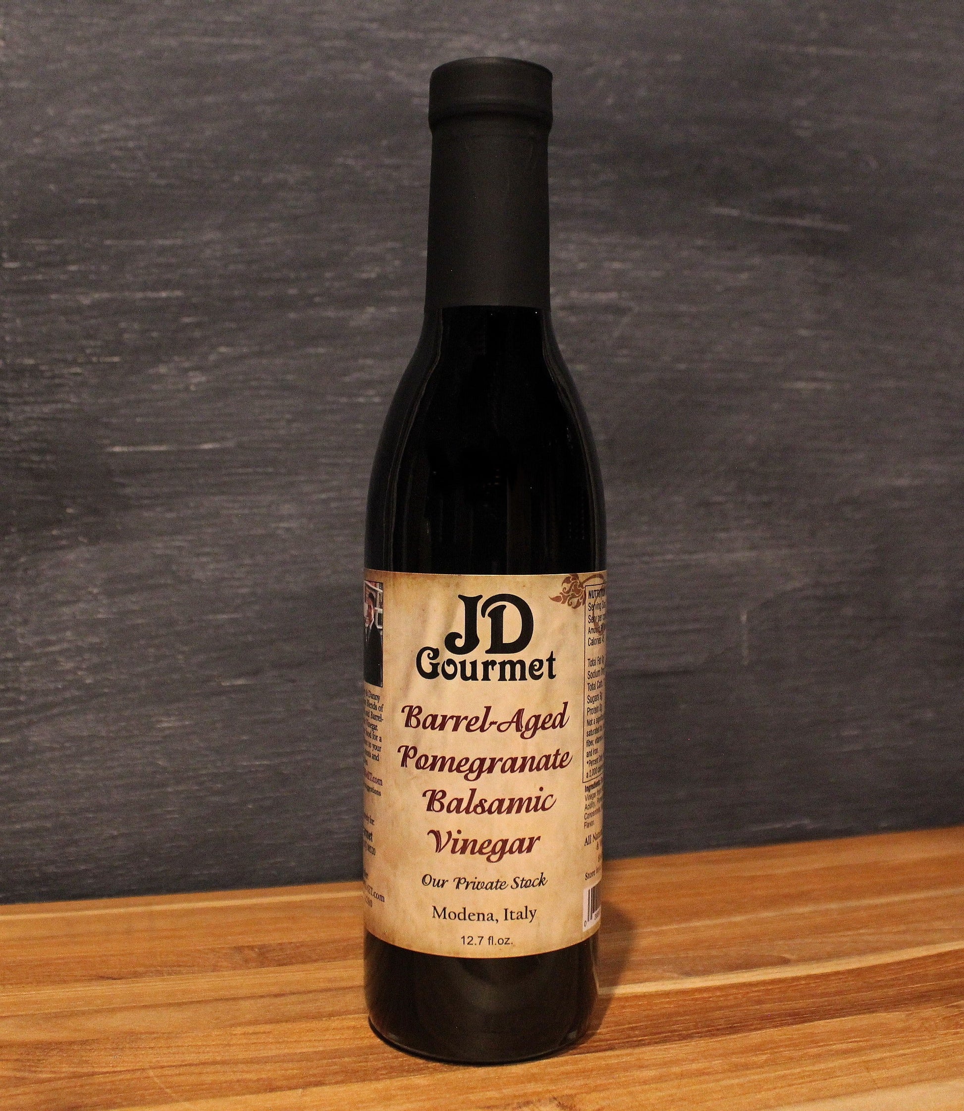 Bottle of JD Gourmet pomegranate balsamic vinegar, deep ruby red and glossy